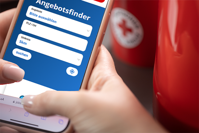 Dieses Imagebild zeigt eine Hand die ein Smartphone hält. Auf dem Smartphone ist die Suchmaske von DRK-Angebote geöffnet.