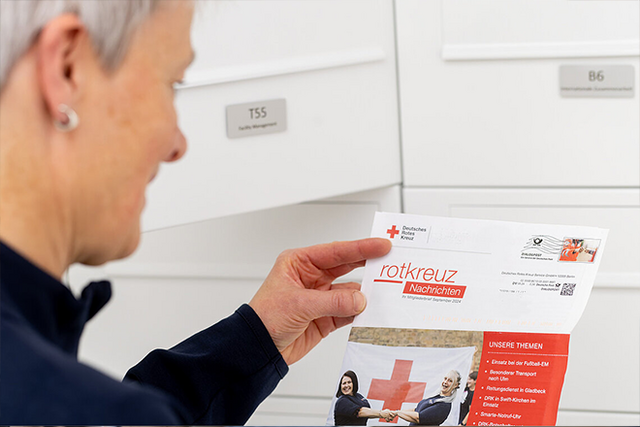 Das Imagebild Teile einer Frau, die den DRK-Mitgliederbrief gerade aus dem Briefkasten genommen hat und diesen liest.
